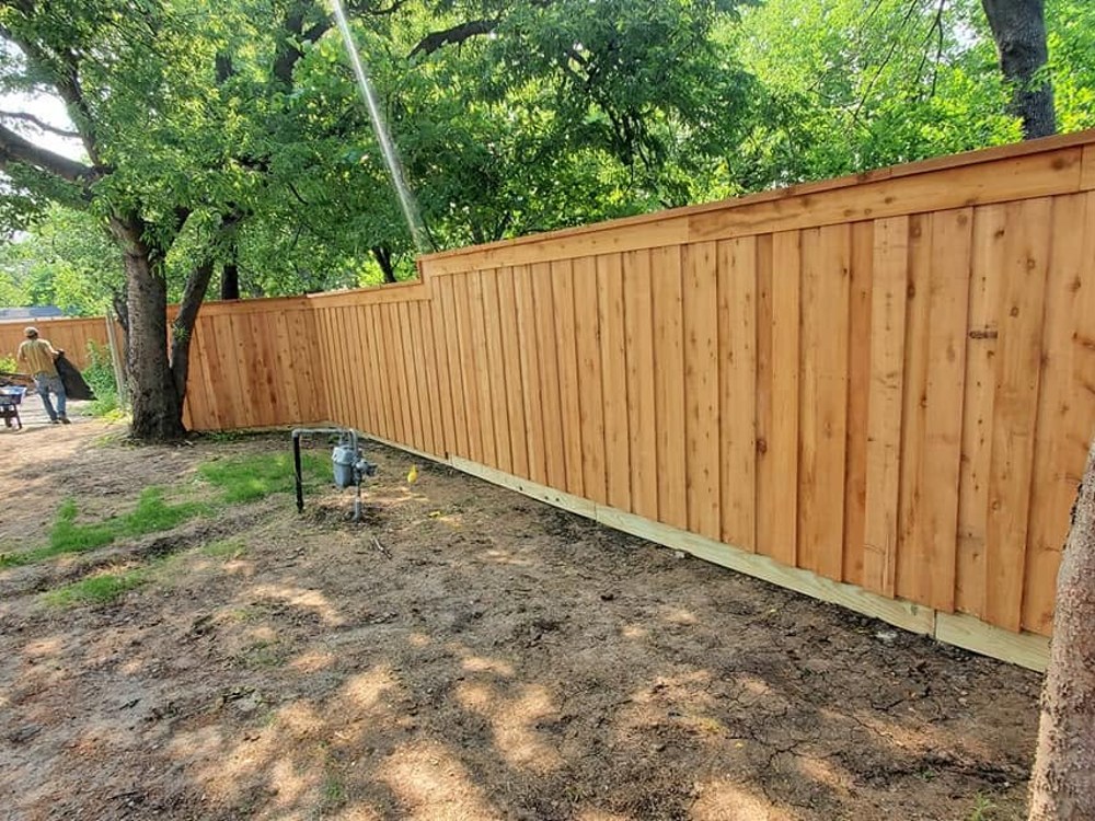 Natural cedar privacy fence along tree-lined backyard