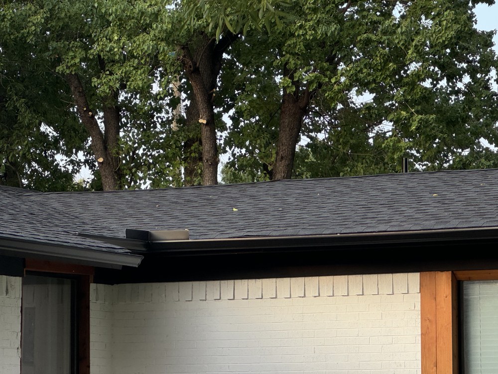 Close-up of finished dark shingle roofline and gutter